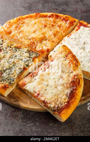 Geschnittene heiße Pizza, vier Käsesorten aus der Nähe auf einem Holzbrett auf dem Tisch. Vertikal Stockfoto