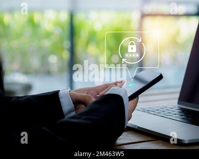 Konzept zum Zurücksetzen des Kennworts. Schlosssymbol, Sicherheitscode wird auf dem Smartphone in den Händen eines Geschäftsmanns angezeigt, während Sie im Büro mit einem Laptop arbeiten Stockfoto