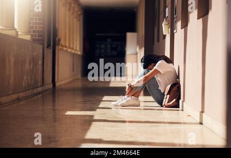 Traurig, einsam und Mädchen mit Depressionen in der Schule, weinend und ängstlich nach Mobbing. Psychische Gesundheit, müde und unglückliche Schülerin im Korridor danach Stockfoto