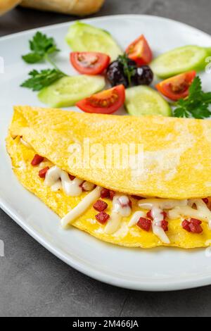 Omelett mit Fetakäse und türkischer Wurst auf einer weißen Porzellanplatte Stockfoto