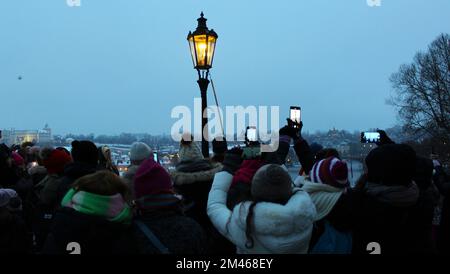 Der Lampenanzünder beleuchtet traditionelle Gaslampen auf der Karlsbrücke im Zentrum von Prag, Tschechische Republik, 18. Dezember 2022. (CTK Photo/Milos Rum Stockfoto