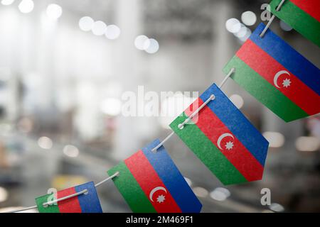 Eine Girlande aserbaidschanischer Nationalflaggen auf abstraktem, verschwommenem Hintergrund. Stockfoto