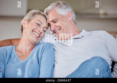 Liebe, Lächeln und Seniorenpaar im Wohnzimmer, Bindung oder Kuscheln. Romantik, Zuneigung und Rentner, älterer und glücklicher Mann und Frau in der Lounge Stockfoto