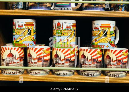 Ungarn, Budapest, 17. juni 2022. Ein Haufen Teetassen als Souvenir mit magyar Wahrzeichen auf einem Regal vom Markt in Budapest. Stockfoto