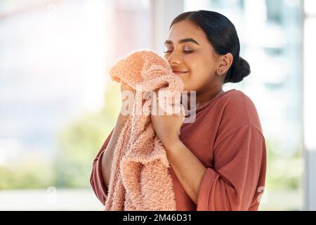 Eine Frau, die nach dem Waschen, Reinigen und dem Housekeeping saubere Wäsche, Decke oder Textilien riecht. Glückliche Frau Stockfoto