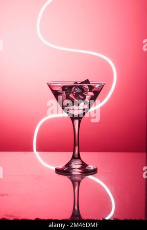 Martini-Glas mit Eis, auf der Bar. Vor dem Hintergrund von Neonlicht. Stockfoto