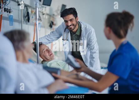 Junger Arzt aus dem Nahen Osten, der während der Untersuchung von Patienten im Krankenzimmer lächelt. Stockfoto