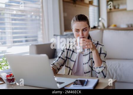 Junge Frau, die Hausaufgaben in ihrer Wohnung hat. Stockfoto