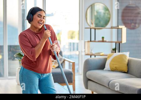 Gesang, Reinigung und Kopfhörer einer Frau mit Musik, die in einem Heim tanzt und glücklich tanzt. Frühjahrsputz, sauberer und glücklicher Mensch singt und Stockfoto