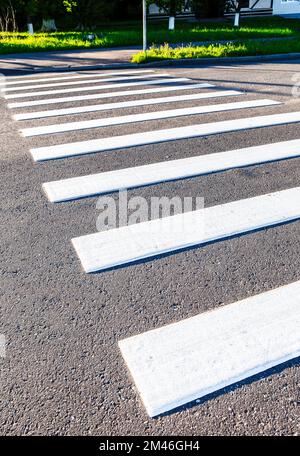 Fußgängerüberquerung mit weißen Streifen auf dem Asphalt. Fußgängerübergang auf der Straße. Struktur des Transporthintergrunds Stockfoto