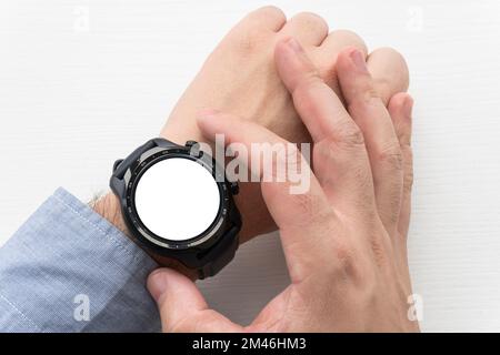 Fitnessuhr am unterarm des manns mit Datum, Uhrzeit, Herzfrequenz und Schrittzähler. Draufsicht Stockfoto
