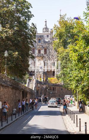 Sintra, Portugal - 14. August 2017: Touristen gehen auf der Straße der Altstadt von Sintra. Der Palast Quinta da Regaleira befindet sich im Hintergrund Stockfoto