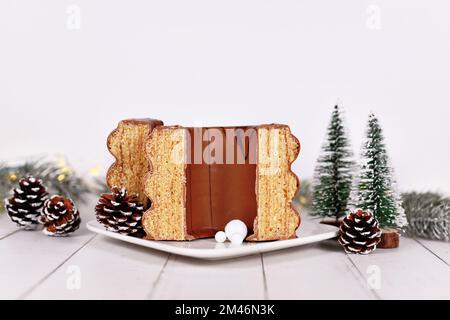 Schneiden Sie den traditionellen, mit Schokolade verglasten, geschichteten Winterkuchen „Baumkuchen“ vor der saisonalen Dekoration auf Stockfoto