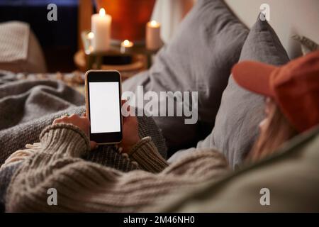 Frau, die im Bett liegt und telefoniert Stockfoto