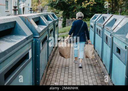 Rückansicht einer Frau, die Papiertüten mit Recycling trägt Stockfoto