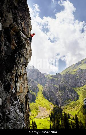 Fit starken Mann Athlet in Silhouette Klettern an der hohen vertikalen Wand an den Bergen Tyan Shan in Kasachstan Stockfoto