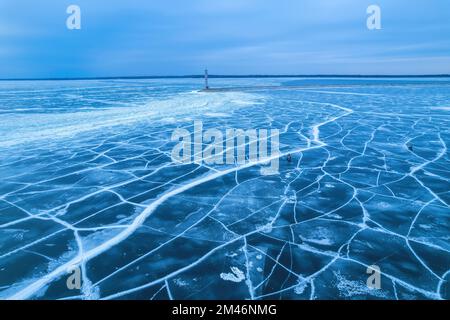 Wellenbrecher, die im Winter in die Ostsee führen. Das Meer ist von Nebel und Eisblöcken bedeckt. Schöner Leuchtturm bei Sonnenaufgang. Stockfoto