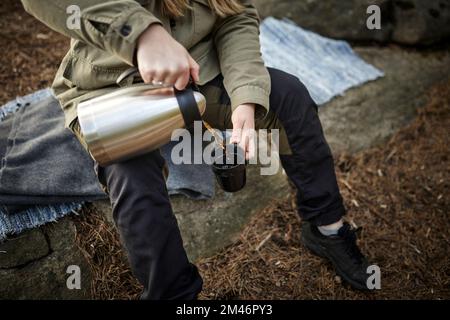 Die Hände gießen Kaffee aus der Thermoskanne Stockfoto