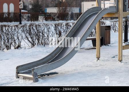 Kinderrutsche auf dem Spielplatz im Winter. Kinderrutsche im Park. Leere Rutsche im Park. Winterattraktion Stockfoto