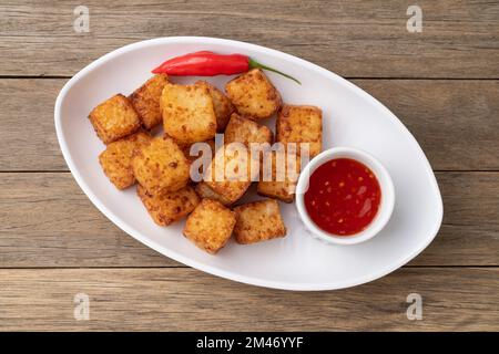 Tapioka-Würfel, typisch nordöstlich brasilianisches Essen mit Chilipfeffersirup auf einem Holztisch. Stockfoto