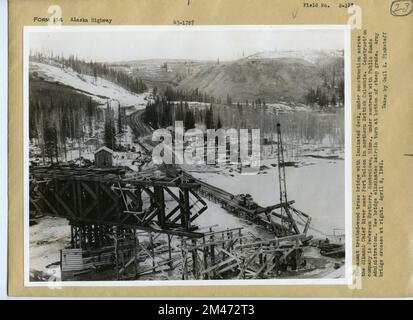 Brückenbau über den Fluss Sikanni Chief. Originalüberschrift: Permanent bearbeitete Holztrassenbrücke mit laminierter Terrasse, die derzeit über den Sikanni Chief River in der Nähe von Fort Nelson im Norden von British Columbia gebaut wird. Das Bauunternehmen ist Pedersen Brothers, Montevideo, Minn., unter Vertrag mit der öffentlichen Straßenverwaltung. Die neue Brücke verhindert das Drehen der Haarnadeln an der Unterseite steiler Gefälle. Armybridge kreuzt rechts. Aufgenommen von Gail K. Pinkstaff, 8. April 1943. Staat: Alaska. Stockfoto