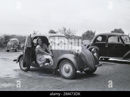 Junge Französin posiert in einem 5 2-türigen Saloon aus dem Vintage Simca, der zwischen 1936 und 1948 in Nanterre Frankreich hergestellt wurde. Das französisch-italienische Auto war identisch mit dem Fiat 500 Topolina. 1951 fotografiert Stockfoto