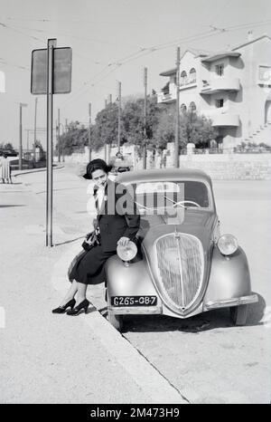 Junge Französin posiert auf dem 5 2-türigen Saloon des Vintage Simca, der zwischen 1836 und 1948 in Nanterre Frankreich hergestellt wurde. Das französisch-italienische Auto war identisch mit dem Fiat 500 Topolina. 1950 in Toulon fotografiert Stockfoto