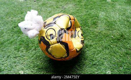 Ein orangefarbener Ball explodierte in einem Garten auf synthetischem Gras Stockfoto