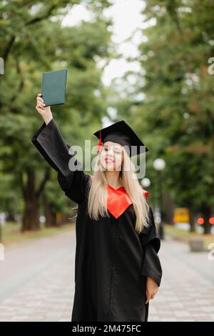 Ein Graduiertenmädchen hält ein Diplom in der Hand Stockfoto