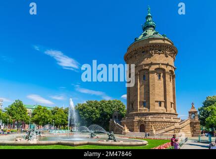 Malerischer Blick auf den berühmten Wasserturm (Wasserturm) und den Brunnen mit Wasserrohren an einem sonnigen Tag mit blauem Himmel in Mannheim,... Stockfoto