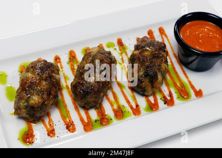 Authentische mediterrane arabische Küche, saftiges Rind- oder Lammfleisch und Käse-Kebab mit würziger roter Harissa-Sauce Stockfoto