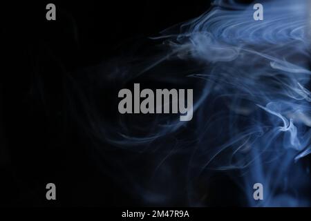 Anmutige Wirbel aus blauem Rauch, isoliert von schwarzem Hintergrund. Nahaufnahme von Dampf. Weichzeichner und Textur von Helios 44m-4-Objektiv im Vintage-Design. Abstrakte Textur. Stockfoto