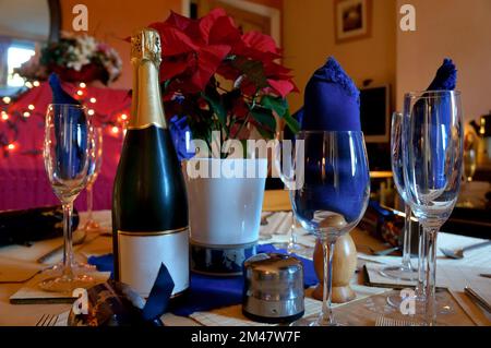 Weinflasche mit Gläsern und Servietten für eine Mahlzeit auf dem Esstisch für Weihnachtsessen mit defokussiertem Hintergrund Stockfoto