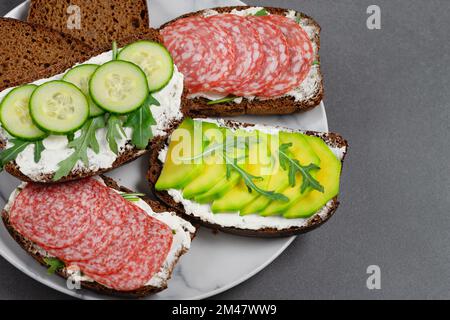 Gesunde Sandwiches mit weißem Hüttenkäse, Gurke, Rucola, Avocado Stockfoto