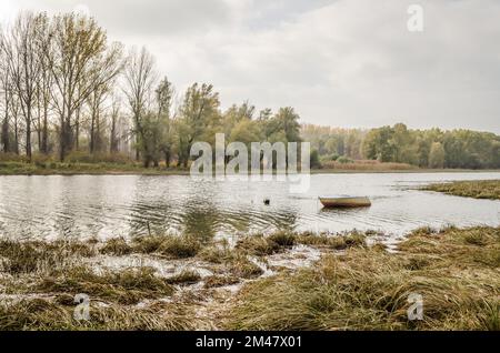 Holzboot am Ufer des Sees im Wasser. Stockfoto