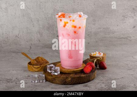 Boba- oder Tapiokapperlen sind taiwanischer Seifenmilchtee in Plastikbecher mit Milchcocktail-Geschmack auf texturiertem Hintergrund, Sommererfrischung. Stockfoto