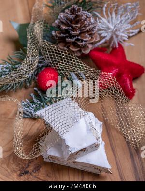 Zwei gestapelte Stücke weißer Mandelnougat mit Weihnachtsdekorationen auf einem Holzbrett Stockfoto