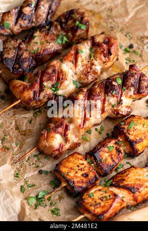 Gebratenes Fleisch auf Holzspießen. Leckere Kebabs in Pflaumensauce, auf Pergament Stockfoto