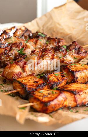 Gebratenes Fleisch auf Holzspießen. Leckere Kebabs in Pflaumensauce, auf Pergament Stockfoto