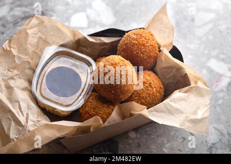 Fleischbällchen, Zutaten geräuchertes Rindfleisch, Milch, Mehl, Käse gefüllt mit Mozzarella. Serviert auf Papiergeschirr. Essen für die Lieferung. Modell für Logo Stockfoto