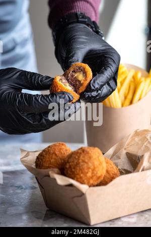 Fleischbällchen, Zutaten geräuchertes Rindfleisch, Milch, Mehl, Käse gefüllt mit Mozzarella. Serviert auf Papiergeschirr. Essen für die Lieferung. Modell für Logo Stockfoto