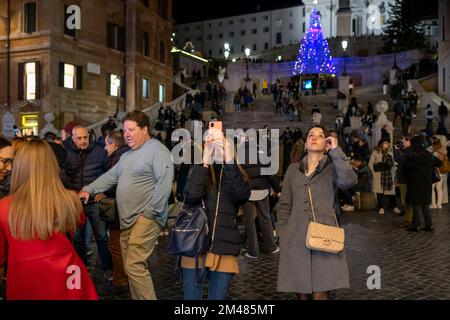 Rom, Italien - 26. November 2022: Zwei Mädchen machen ein Selfie mit ihrem Handy auf der überfüllten Piazza di Spagna, die mit Weihnachtslichtern dekoriert ist. Stockfoto