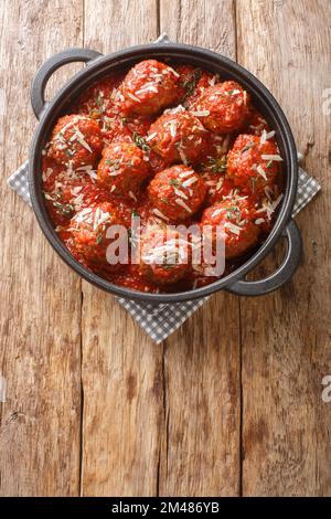 Fleischbällchen in Tomatensoße in einer Pfanne auf Holzhintergrund. Vertikale Draufsicht von oben Stockfoto