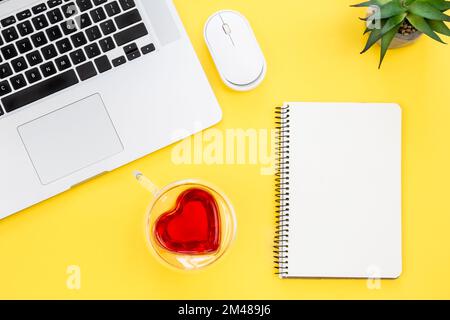 Laptop und leerer Notizblock auf gelbem Hintergrund, flach liegend. Stockfoto