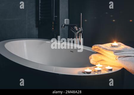 Badezimmer mit Handtüchern und Kerzen in der Nacht. Stockfoto