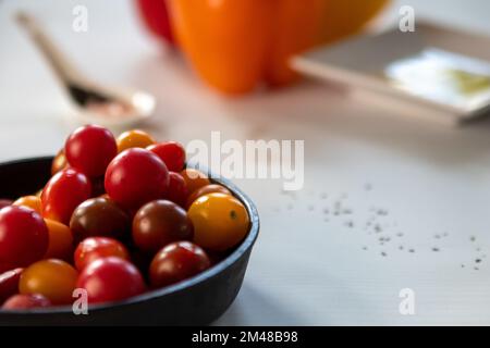 Kirschtomaten in gut gebrauchtem Gusseisen mit Salz, Pfefferöl und rotem Paprika. Stockfoto
