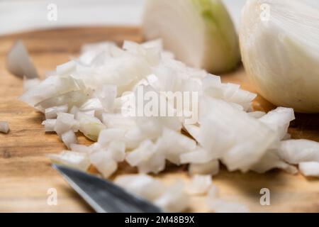 Gewürfelte Zwiebel auf einem hölzernen Schneidebrett. Weiße Zwiebel in Scheiben. Stockfoto