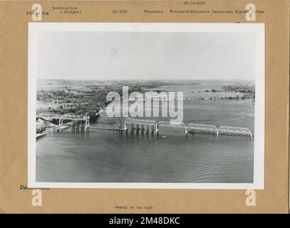 Wisconsin - Minnesota Interstate Highway Bridge. Originalunterschrift: Wisconsin - Minnesota Interstate Highway Bridge an der U.S. 12. Ein Luftblick auf die gesamte Brücke mit Blick nach Norden oder flussaufwärts. Die alte Mautbrücke und die Omaha Railroad Bridge im Hintergrund. Minnesotas Küste links vom Bild. Bau der fast 800 m langen Brücke über die St. Croix River nähert sich der Fertigstellung. Kredit: Minneapolis Sunday Tribune. Bundesstaat: Wisconsin. Ort: Hudson. Stockfoto