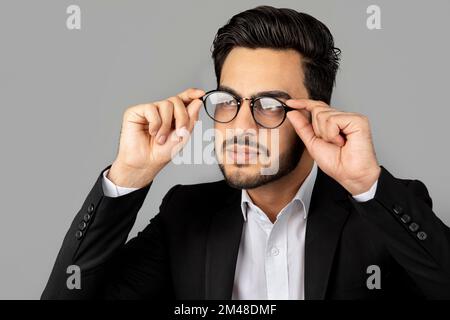 Porträt Eines Gutaussehenden Jungen Arabischen Geschäftsmanns Mit Anzug Und Brille, Der Wegschaut Stockfoto