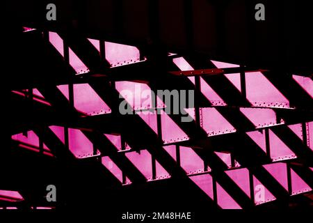 Sonnenlicht und Schatten in hohem Kontrast auf der NYC-Infrastruktur mit Stahlträger in Viva Magenta Stockfoto